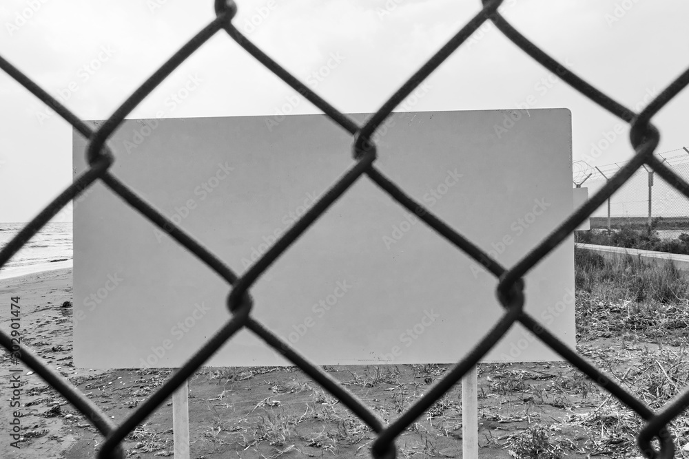 Fototapeta premium Blank danger or warning sign through wire mesh fence