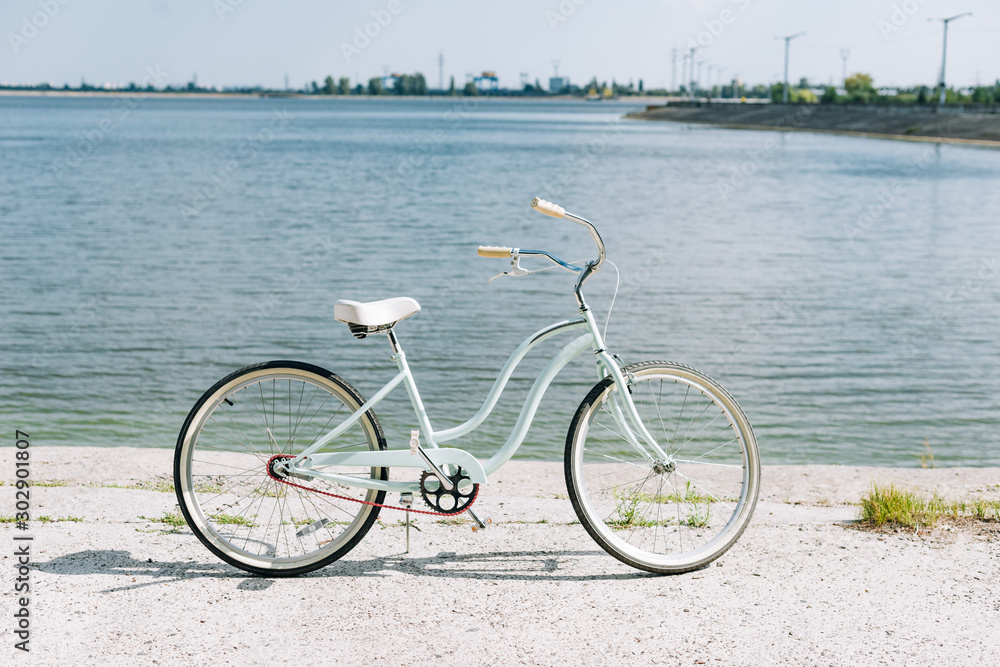 Fototapeta premium side view of bicycle near blue river in summer in sunshine