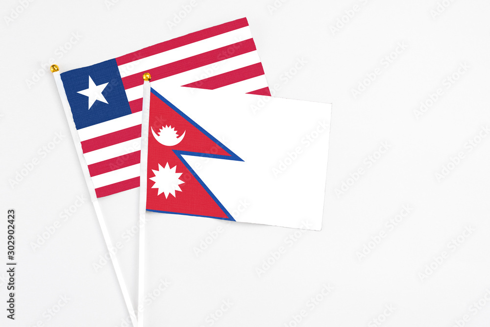 Nepal and Liberia stick flags on white background. High quality fabric, miniature national flag. Peaceful global concept.White floor for copy space. Nepal and Liberia stick flags on white background. High quality fabric, miniature national flag. Peaceful global concept.White floor for copy space.