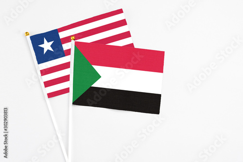 Sudan and Liberia stick flags on white background. High quality fabric  miniature national flag. Peaceful global concept.White floor for copy space.