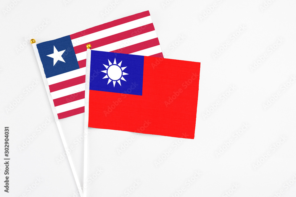 Fototapeta premium Taiwan and Liberia stick flags on white background. High quality fabric, miniature national flag. Peaceful global concept.White floor for copy space.