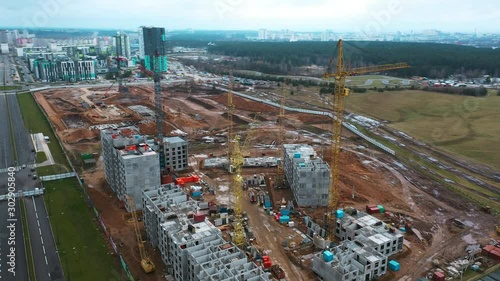 Drone fly around construction crane, development process of high rise block of flats, tower block apartment building. Sleeping area in ecologically clean area near forest away noisy city.