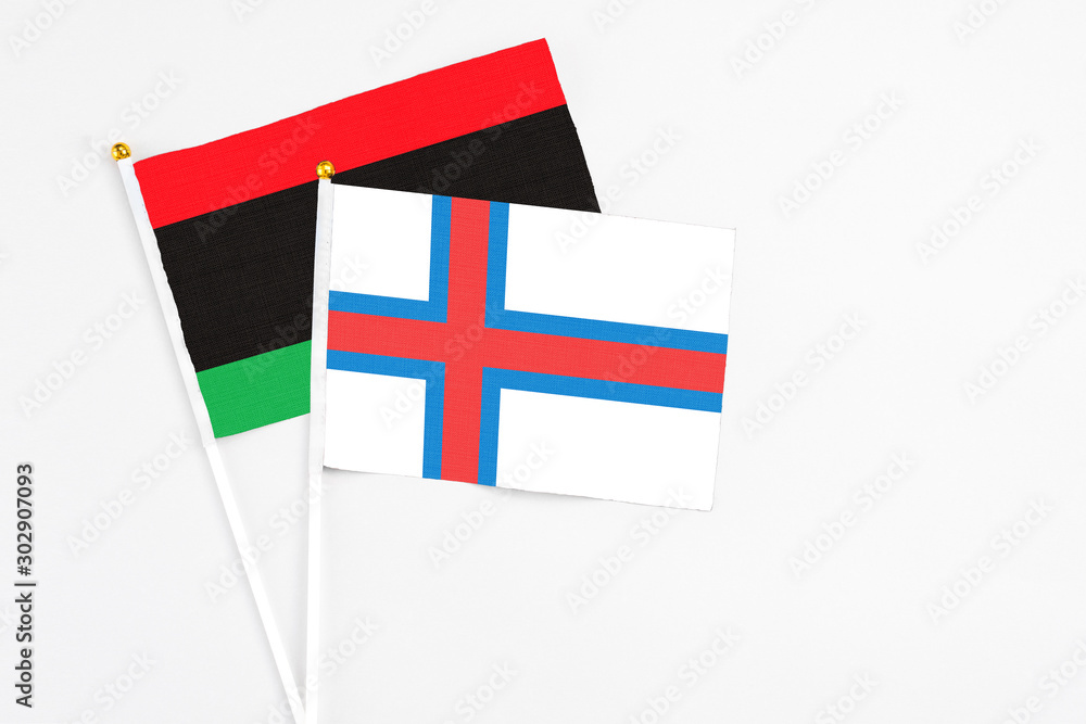 Faroe Islands and Libya stick flags on white background. High quality fabric, miniature national flag. Peaceful global concept.White floor for copy space.