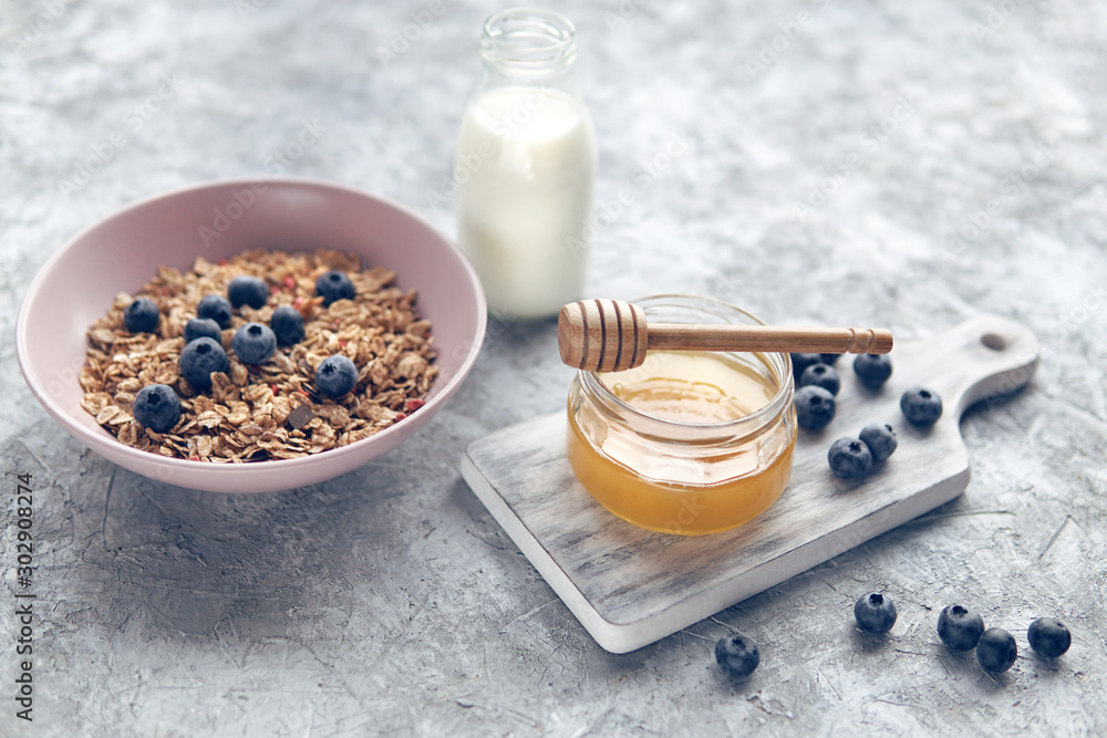 Healthy food background with homemade oatmeal granola or muesli, bottle of milk, honey and fresh berries for healthy morning breakfast. Selective focus. Healthy food background with homemade oatmeal granola or muesli, bottle of milk, honey and fresh berries for healthy morning breakfast. Selective focus.