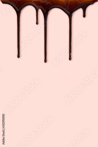 Minimal dark chocolate pouring drop on pastel pink background