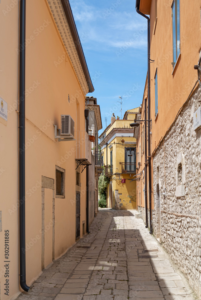 Fototapeta premium A narrow street among the old houses of a medieval town in Venosa Italy