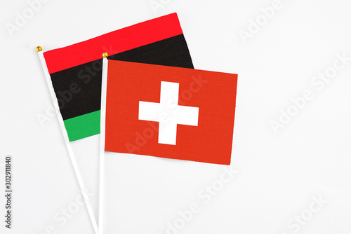 Switzerland and Libya stick flags on white background. High quality fabric, miniature national flag. Peaceful global concept.White floor for copy space. photo