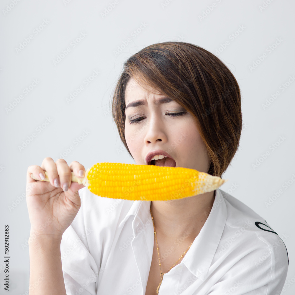 Asian girl eating yellow corn at home. Asian girl eating yellow corn at home.