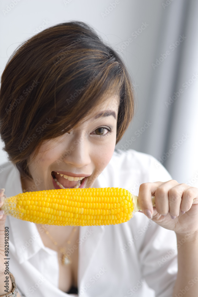 Asian girl eating yellow corn at home. Asian girl eating yellow corn at home.