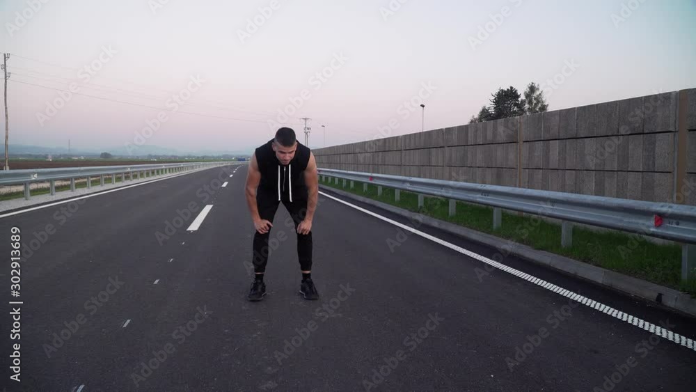 4k video of young fit man running closer to the camera exhausted, outdoors on the empty street