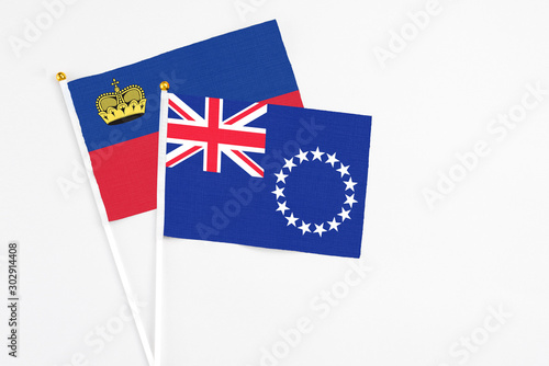 Cook Islands and Liechtenstein stick flags on white background. High quality fabric, miniature national flag. Peaceful global concept.White floor for copy space.