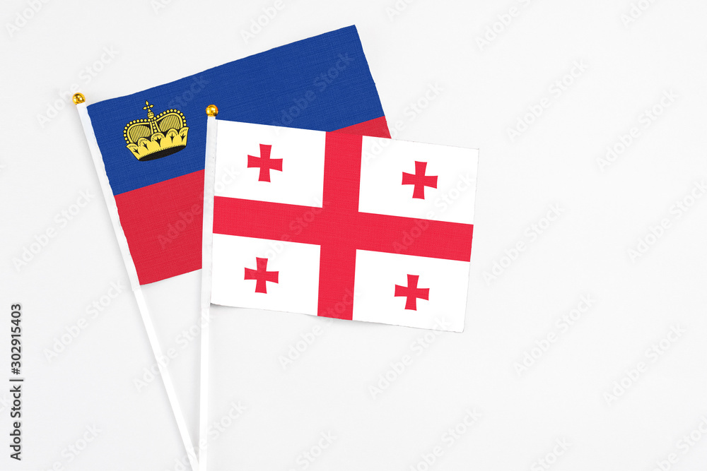 Georgia and Liechtenstein stick flags on white background. High quality fabric, miniature national flag. Peaceful global concept.White floor for copy space.