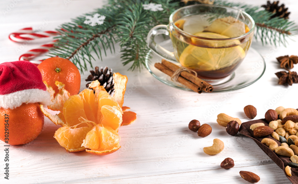 Christmas tea, nuts and tangerines on a white wooden background