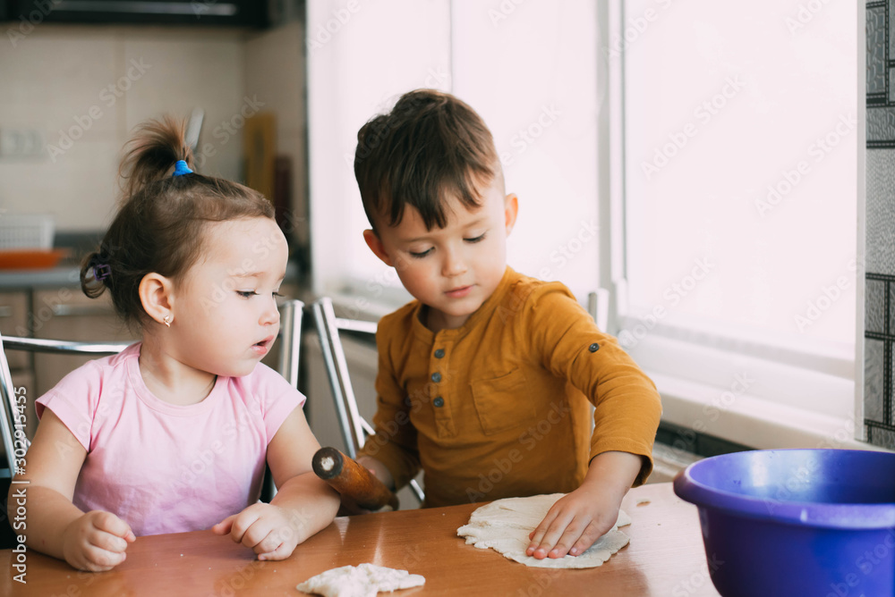 Children, brother and sister during the day in the kitchen prepare pastry or pizza or pie Children, brother and sister during the day in the kitchen prepare pastry or pizza or pie