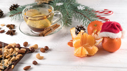 Christmas tea, nuts and tangerines on a white wooden background