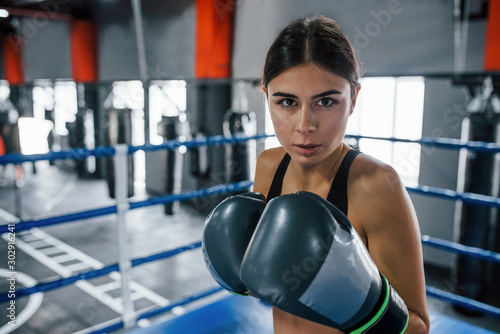 Young woman in sportive wear is in the boxing ring having exercise day
