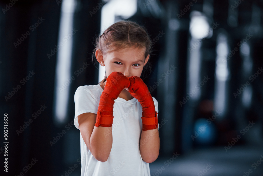 Portrait of young little girl in sportive wear that is in the gym have exercise day. Conception of boxing Portrait of young little girl in sportive wear that is in the gym have exercise day. Conception of boxing