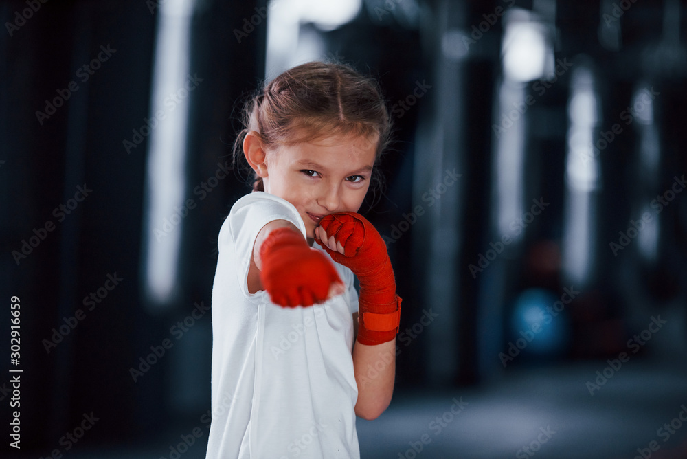 Portrait of young little girl in sportive wear that is in the gym have exercise day. Conception of boxing Portrait of young little girl in sportive wear that is in the gym have exercise day. Conception of boxing