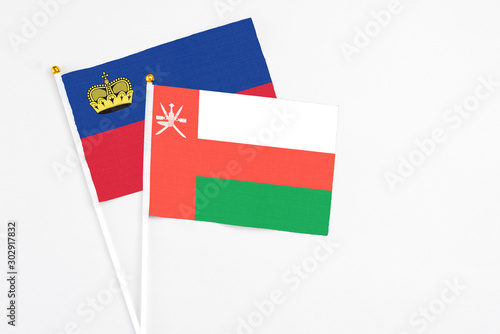 Oman and Liechtenstein stick flags on white background. High quality fabric  miniature national flag. Peaceful global concept.White floor for copy space.