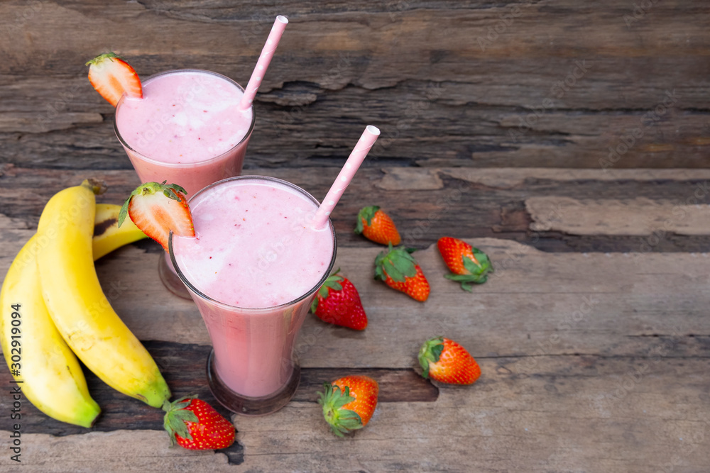 Strawberry and banana smoothie colorful fruit juice milkshake blend beverage healthy high protein the taste yummy In glass drink episode morning on a wooden background. Strawberry and banana smoothie colorful fruit juice milkshake blend beverage healthy high protein the taste yummy In glass drink episode morning on a wooden background.