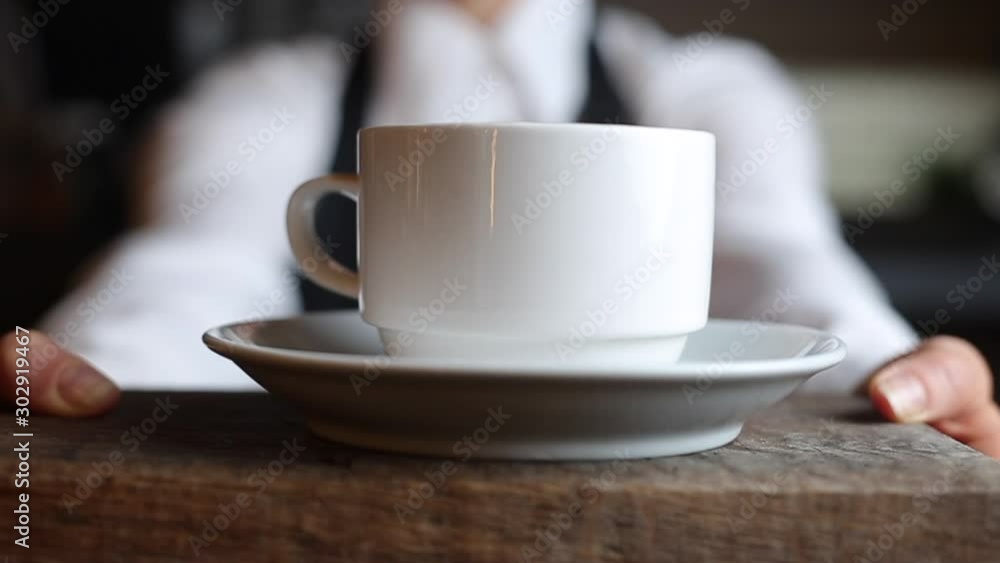 Barista girl in an apron gives a cup of coffee to a cafe client. Barista girl in an apron gives a cup of coffee to a cafe client.