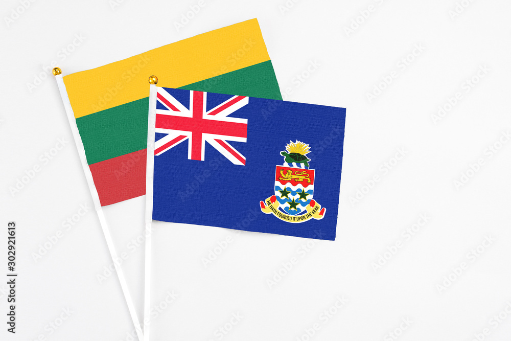 Fototapeta premium Cayman Islands and Lithuania stick flags on white background. High quality fabric, miniature national flag. Peaceful global concept.White floor for copy space.