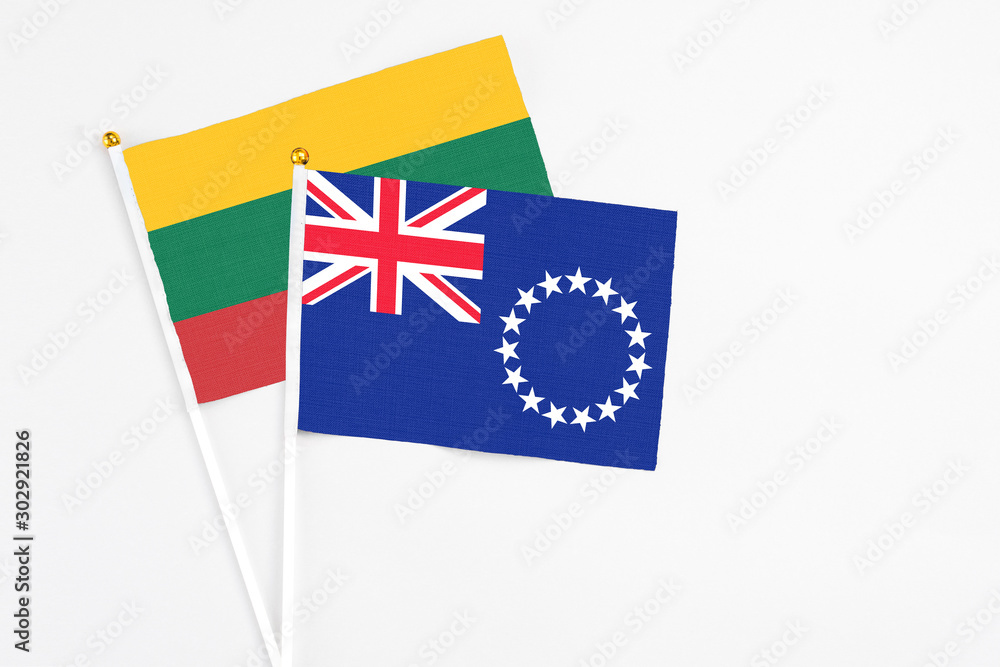 Fototapeta premium Cook Islands and Lithuania stick flags on white background. High quality fabric, miniature national flag. Peaceful global concept.White floor for copy space.