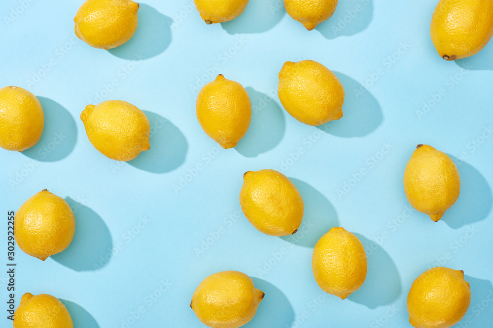 top view of ripe yellow lemons on blue background with shadows