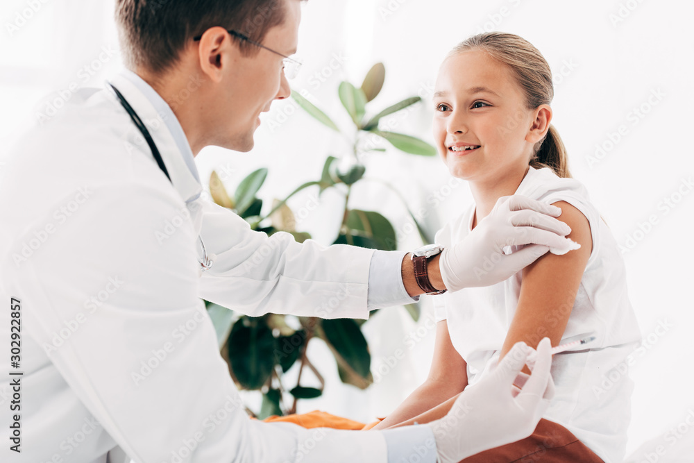 Obraz premium pediatrist in latex gloves doing injection to child