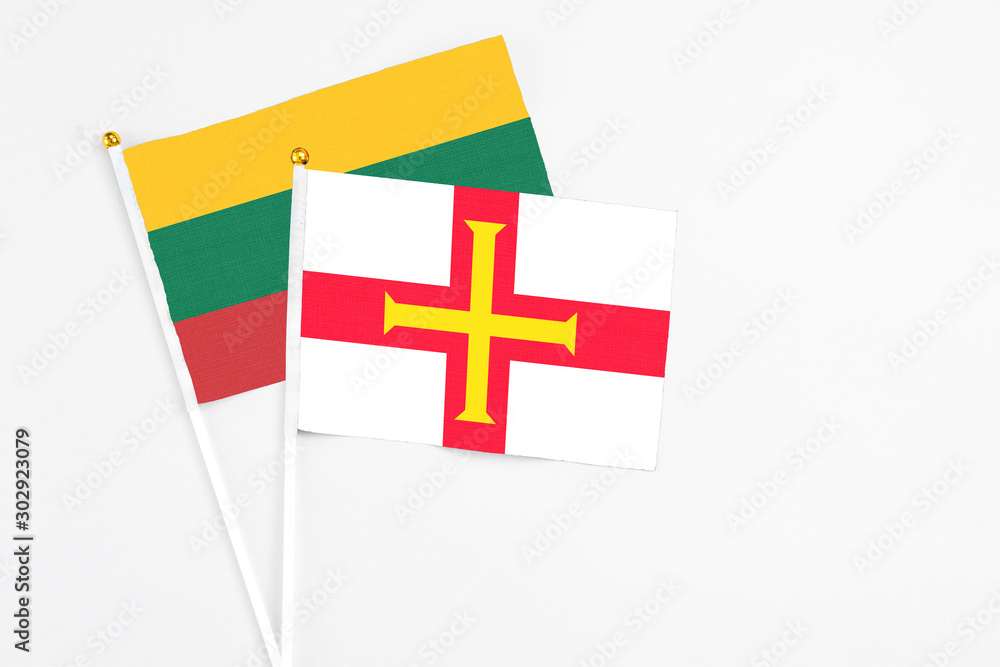 Guernsey and Lithuania stick flags on white background. High quality fabric, miniature national flag. Peaceful global concept.White floor for copy space.