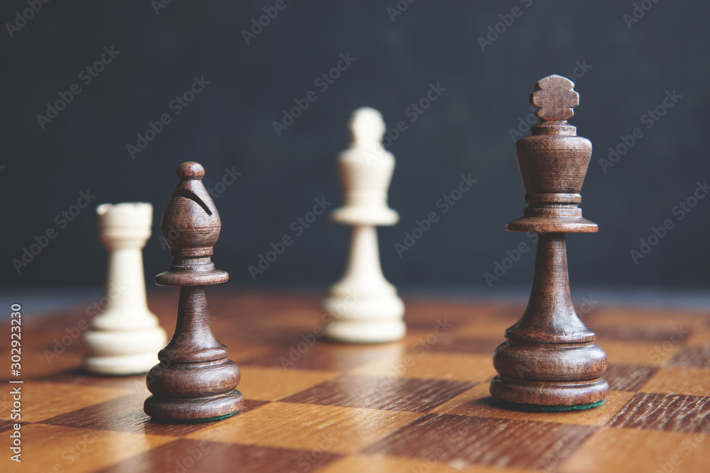 Chess game - checkmate situation on old chessboard. Game is over. Dark background, selective focus, copy space Chess game - checkmate situation on old chessboard. Game is over. Dark background, selective focus, copy space