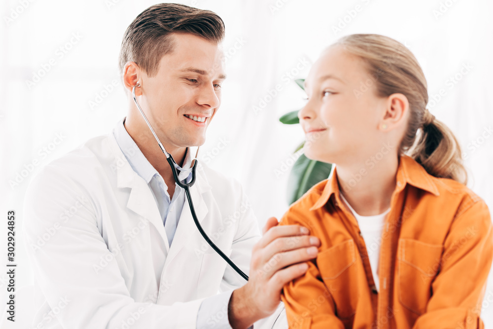 pediatrist in white coat examining kid with stethoscope pediatrist in white coat examining kid with stethoscope