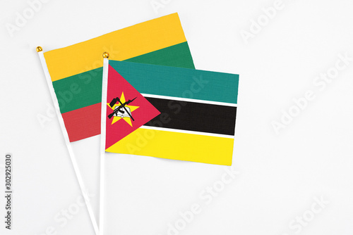 Mozambique and Lithuania stick flags on white background. High quality fabric  miniature national flag. Peaceful global concept.White floor for copy space.