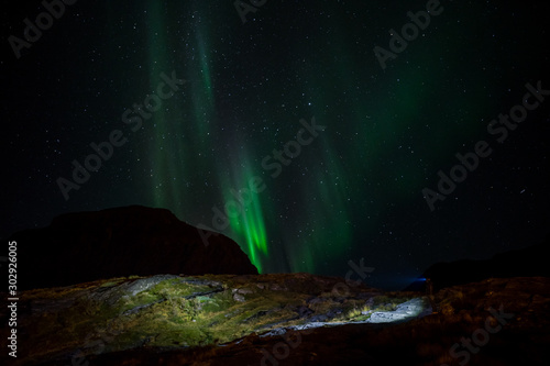 Man with flashlight and northern lights on sky