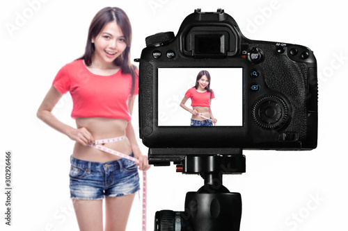 Asian vlogger measuring waist behind camera, social media concept