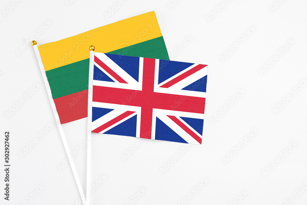 Fototapeta premium United Kingdom and Lithuania stick flags on white background. High quality fabric, miniature national flag. Peaceful global concept.White floor for copy space.