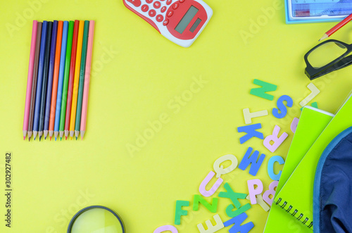 Student backpack and various school supplies. Studying, education and back to school concept. Yellow background and selective focus.