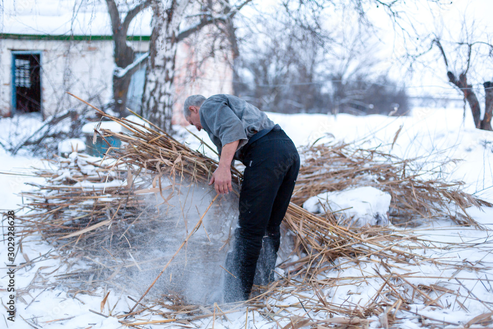A man shelters a dry reed field, heats plants in winter A man shelters a dry reed field, heats plants in winter