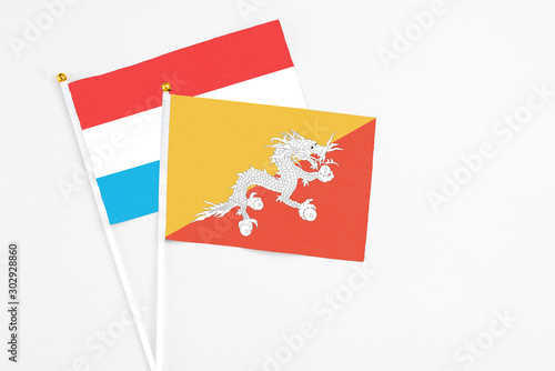 Bhutan and Luxembourg stick flags on white background. High quality fabric, miniature national flag. Peaceful global concept.White floor for copy space.