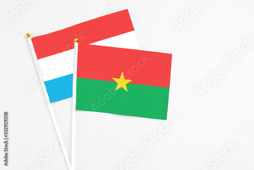 Burkina Faso and Luxembourg stick flags on white background. High quality fabric, miniature national flag. Peaceful global concept.White floor for copy space.