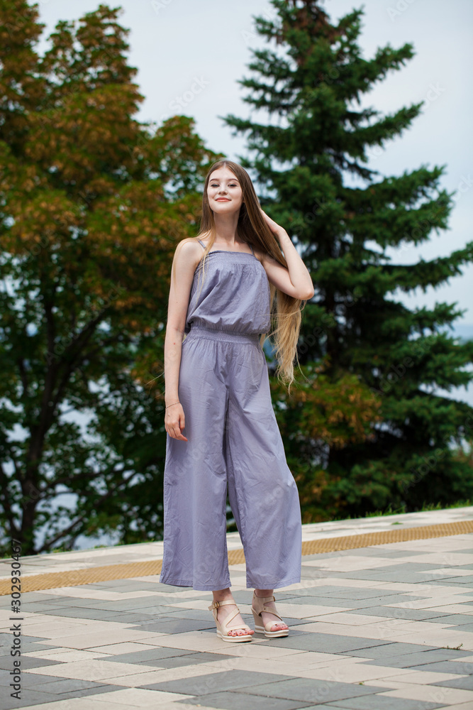 Young beautiful blonde woman in summer dress posing in summer park Young beautiful blonde woman in summer dress posing in summer park