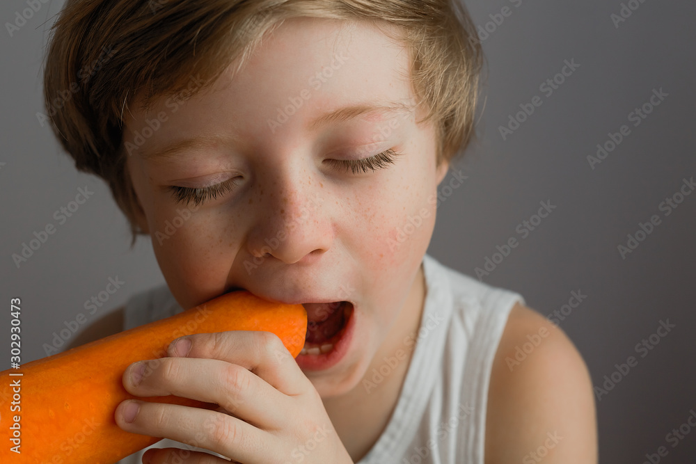 Portrait of a boy biting an orange large carrot Portrait of a boy biting an orange large carrot