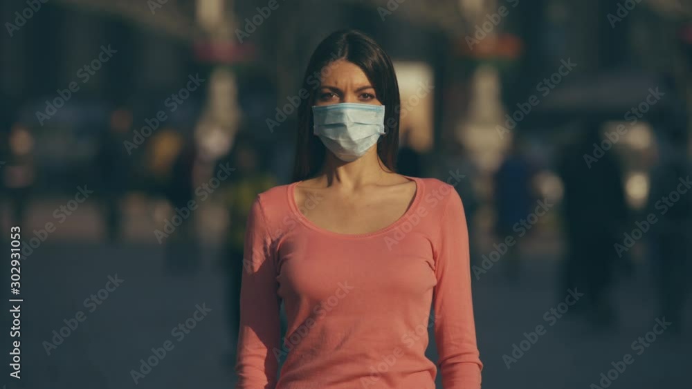 The woman with medical face mask stands in a crowded street The woman with medical face mask stands in a crowded street