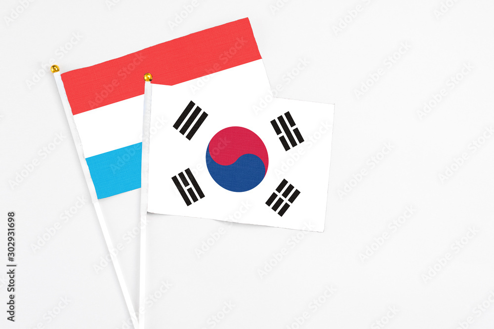 South Korea and Luxembourg stick flags on white background. High quality fabric, miniature national flag. Peaceful global concept.White floor for copy space.
