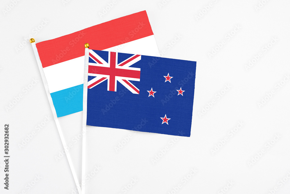 Fototapeta premium New Zealand and Luxembourg stick flags on white background. High quality fabric, miniature national flag. Peaceful global concept.White floor for copy space.