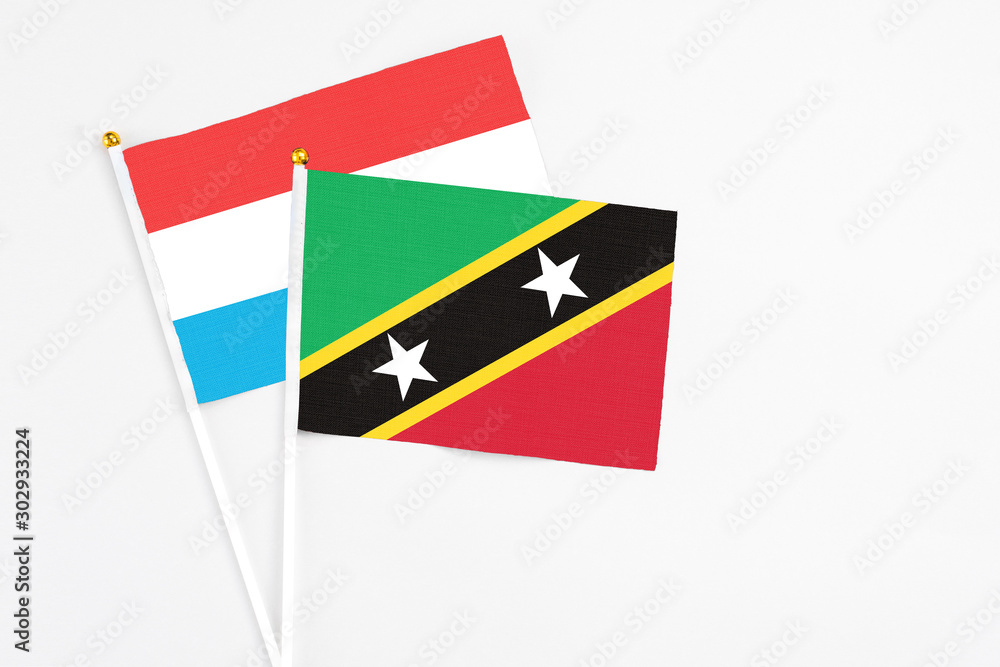 Saint Kitts And Nevis and Luxembourg stick flags on white background. High quality fabric, miniature national flag. Peaceful global concept.White floor for copy space.