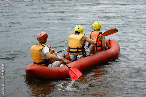 The occupation of active sports. Riding on the rapids on an inflatable boat. Three young people are engaged in rafting.