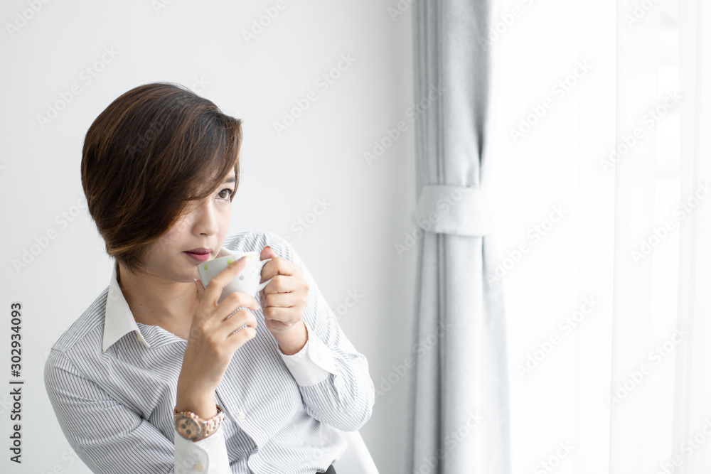 Businesswoman drinking coffee and looking out window. Businesswoman drinking coffee and looking out window.