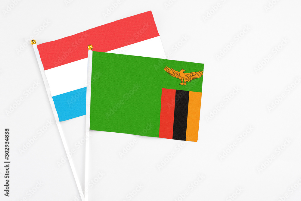 Zambia and Luxembourg stick flags on white background. High quality fabric, miniature national flag. Peaceful global concept.White floor for copy space.