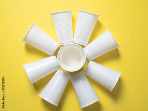 white disposable cups stand on a yellow background laid out in the shape of the sun